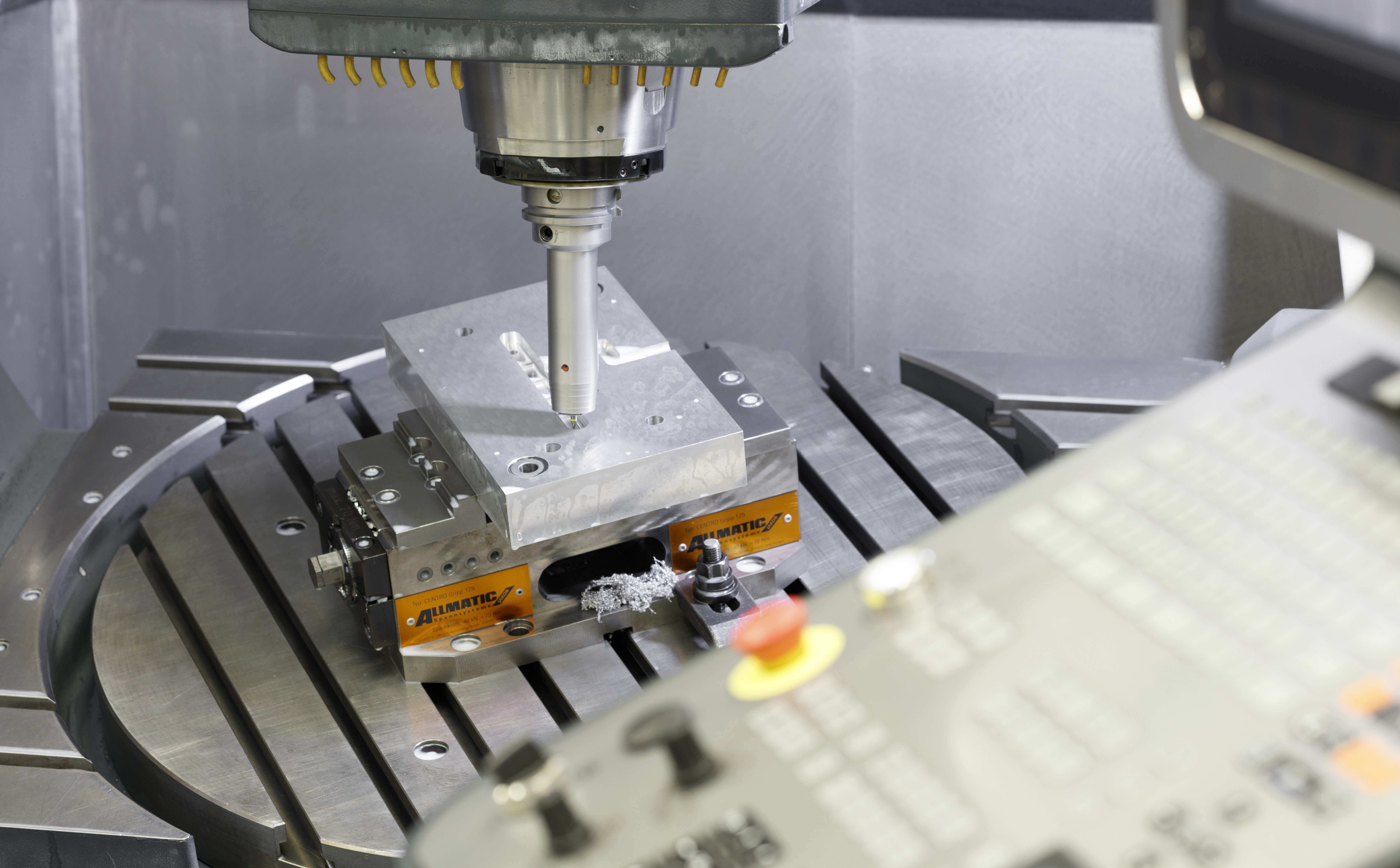 Ausbildung-Werkzeugmechaniker – Feinguss Lobenstein Ein Werkzeug einer Maschine bearbeitet präzise ein Metallwerkstück auf einer festen Spannvorrichtung. Die Szene zeigt einen industriellen Fertigungsprozess mit hoher Genauigkeit.